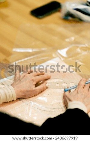 close-up in a sewing workshop the artist’s hands draw a sketch of clothes