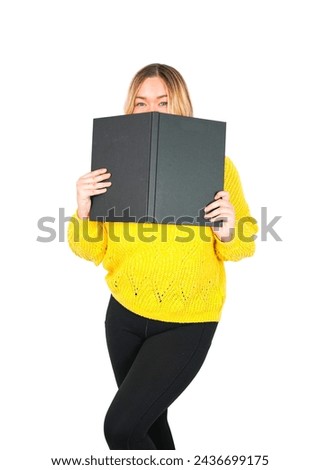 Beautiful young blonde female teacher covering her face with a black book against a white background