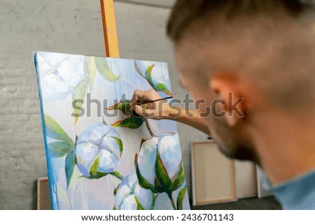 in an art studio painting with flowers the artist sitting the details on the painting with red paint