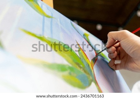 close up in an art studio painting with flowers the artist sitting the details on the painting with red paint