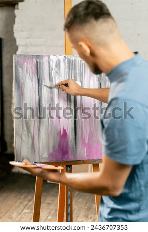 in an art studio an artist mixes color on a palette holding in his hands