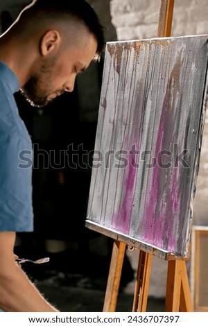 in an art studio an artist stands near painting thinking about the next step