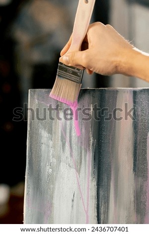 close-up from below in an art workshop the artist makes pink streaks on canvas