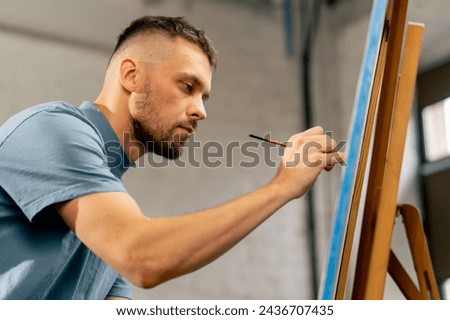 in the art studio of an artist painting close to a painting with a red brush