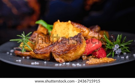 On a black porcelain plate, rack of lamb with fried polenta and hot peppers. Restaurant menu. Homemade food. Very beautiful and appetizing. Royalty-Free Stock Photo #2436715915