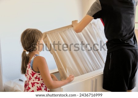 An adult and a child unpacking new furniture to enhance and improve their living space. a warm, family-friendly atmosphere, emphasizing the practicality and aesthetic appeal of the furniture. 