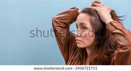 Portrait of the female person in a brown eco-leather dress making hairstyle herself. A woman is preparing to go to a meeting. Banner with copy space.