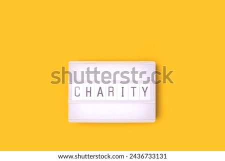 Word Charity. White lightbox with letters on a yellow background. 