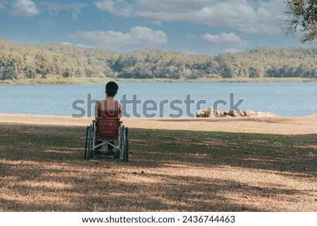 Back of young boy sitting on wheelchair looking at beautiful nature park, Traveling using a wheel chair to learn about the world without limits with support from family,Good mental health,positive pic