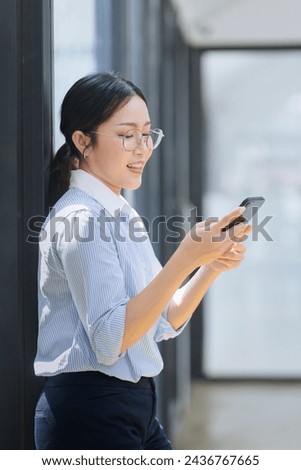 Asian businesswoman using smartphone standing at the office. 