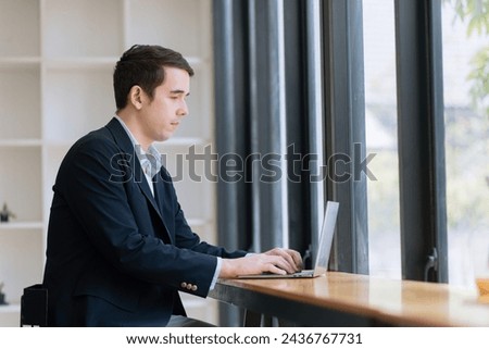 Businessman using laptop sitting at desk in office.