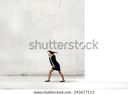 Young determined businesswoman pulling white blank banner with rope
