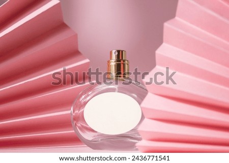 Perfume bottle with paper fan. Concept of expensive perfume and cosmetics. Floral fragrance for women. Perfume spray. Modern luxury lady parfum de toilette Royalty-Free Stock Photo #2436771541