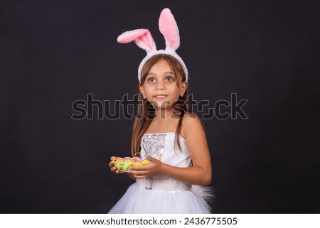 Cute little girl wearing bunny ears on Easter day. Girl holding basket with painted eggs. Royalty-Free Stock Photo #2436775505