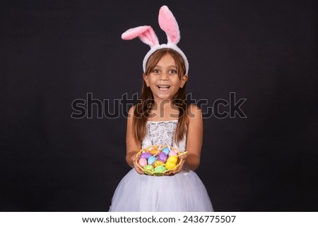 Cute little girl wearing bunny ears on Easter day. Girl holding basket with painted eggs. Royalty-Free Stock Photo #2436775507