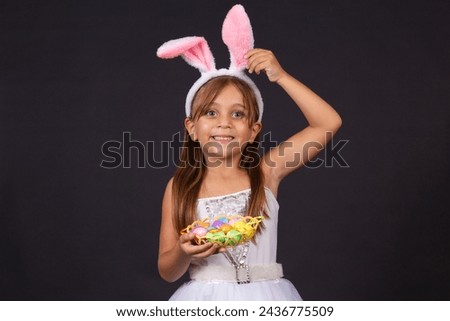 Cute little girl wearing bunny ears on Easter day. Girl holding basket with painted eggs. Royalty-Free Stock Photo #2436775509