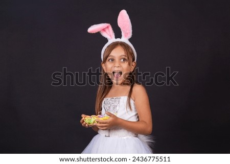 Cute little girl wearing bunny ears on Easter day. Girl holding basket with painted eggs. Royalty-Free Stock Photo #2436775511