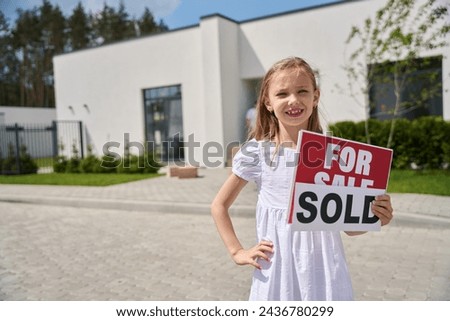 Child in white dress stands with signs for sale, sold