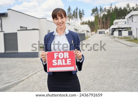 Lady in a business suit has for sale sign in her hands