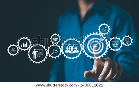 Business strategy and goals concept visualization. Businessman with the virtual interface of cogwheels representing business strategies and objectives. Startup investment, Growth target, Planning,