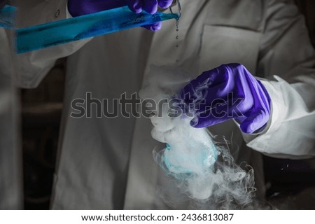 Smoky experiments with blue droplets. Scientist working on chemical reaction, generating thick smoke from a glass flask. Copyspace