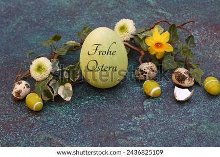 Happy Easter greeting card: Harmonious Easter decoration with Easter eggs in a nest, one of which is inscribed with the text Happy Easter.	The German inscription translates as Frohe Ostern. Royalty-Free Stock Photo #2436825109
