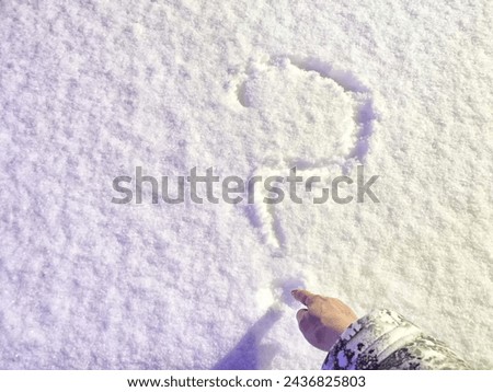 Question mark written in the snow and hand. The cold frosty texture of the snow and the question mark. Background, place for text, copy space