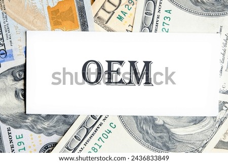OEM original equipment manufacturer concept. Text on a white business card against the background of money, a business concept