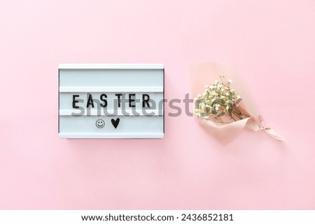 Lightbox with text Easter and bouquet gypsophila on pink background. Concept Easter style. Creative composition Flat lay.  Greeting card. Top view. Happy Easter led sign and flowers.  Royalty-Free Stock Photo #2436852181