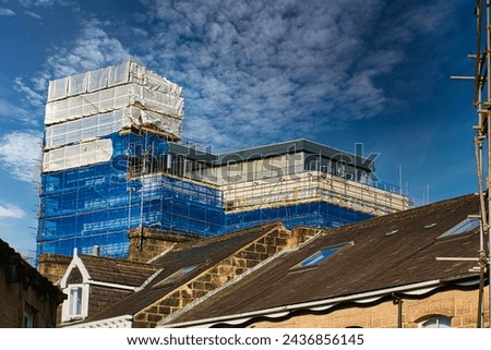 Building under construction with scaffolding against a blue sky with clouds in Harrogate, England. Royalty-Free Stock Photo #2436856145