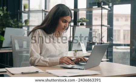 Arabian stressed businesswoman gen z Indian business woman working in office with computer laptop and paperwork problem failure search information trouble with documents difficulties financial mistake Royalty-Free Stock Photo #2436863391