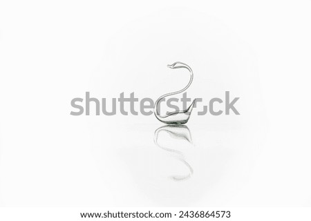 Glass swan with reflection is isolated on white background. Glass swan figurine. Perfect symbol of forever love - swan made of transparent glass. 
