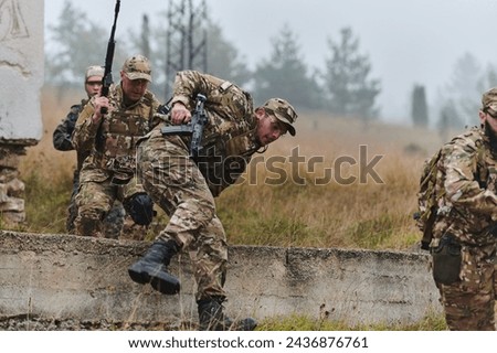 A highly trained elite military unit, clad in camouflage, skillfully navigates through perilous forest terrain, overcoming obstacles and executing a precise and covert mission Royalty-Free Stock Photo #2436876761