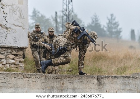A highly trained elite military unit, clad in camouflage, skillfully navigates through perilous forest terrain, overcoming obstacles and executing a precise and covert mission Royalty-Free Stock Photo #2436876771