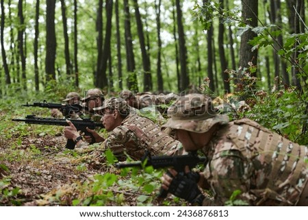 Elite soldiers stealthily maneuver through the dense forest, camouflaged in specialized gear, as they embark on a covert and strategic military mission Royalty-Free Stock Photo #2436876813