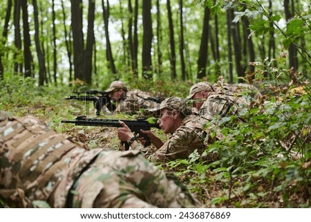 Elite soldiers stealthily maneuver through the dense forest, camouflaged in specialized gear, as they embark on a covert and strategic military mission Royalty-Free Stock Photo #2436876869