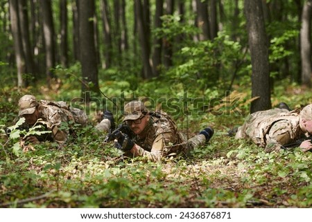 Elite soldiers stealthily maneuver through the dense forest, camouflaged in specialized gear, as they embark on a covert and strategic military mission Royalty-Free Stock Photo #2436876871
