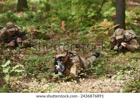 Elite soldiers stealthily maneuver through the dense forest, camouflaged in specialized gear, as they embark on a covert and strategic military mission Royalty-Free Stock Photo #2436876891