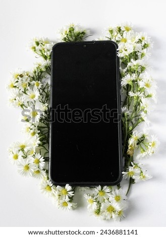 a cellphone surrounded by white flowers on white paper
