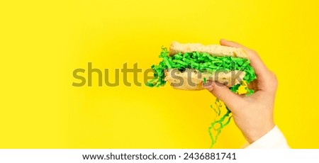 A teenage girl holds a bread sandwich with Easter green hay.