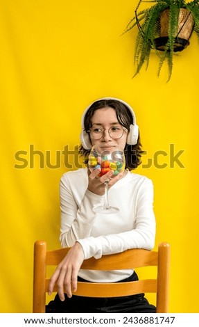 A teenage girl holds a wine glass with Easter eggs.