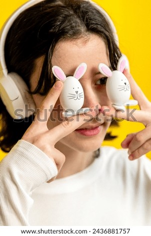 A teenage girl holds two Easter bunny in front of her eyes.