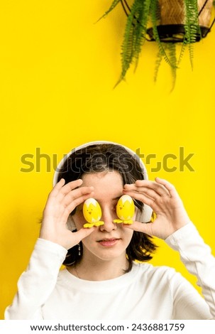 A teenage girl holds two Easter chickens in front of her eyes.