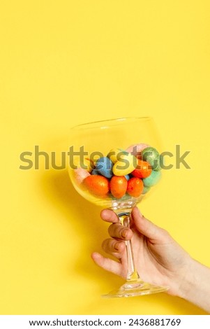 The girl hand holds a glass with Easter eggs.