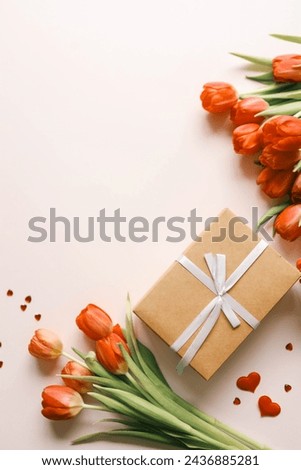 Gift box with a bow and a bouquet of red tulips, top view, background.