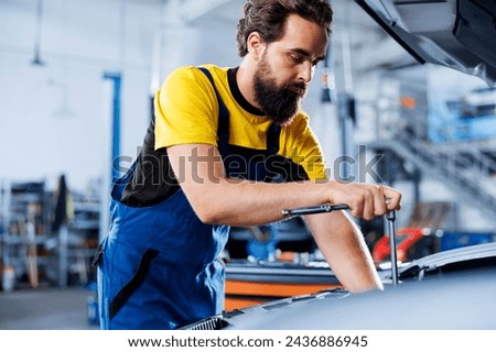 Repairman in car service uses torque wrench to tighten bolts after replacing compressor belt. Trained auto repair shop worker uses professional tools to fix customer automobile Royalty-Free Stock Photo #2436886945