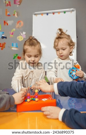 Two toddler are deeply focused on sorting colorful beads during an educational play session in classroom.