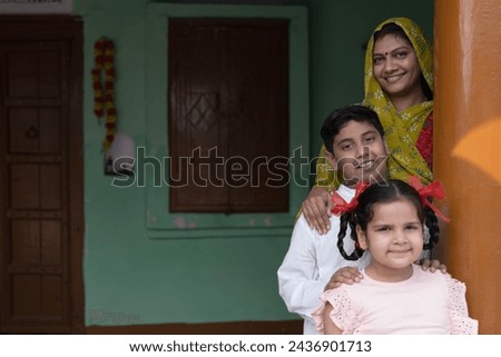 Indian happy rural family. Happy indian rural mother with little daughter and son looking camera at home. Royalty-Free Stock Photo #2436901713