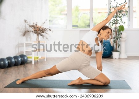 Experienced girl fitness club teacher performs deadbolt pose, parighasana. Concept of development, healthy lifestyle