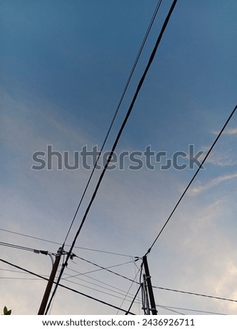 "Tiang listrik" electric pillars with lots of high voltage wires are located by the side of the road Royalty-Free Stock Photo #2436926711